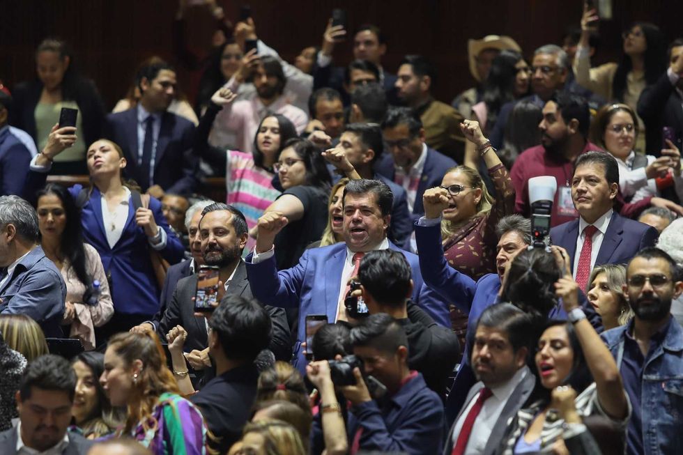 Crowd of people raising fists and taking photos at a formal event.