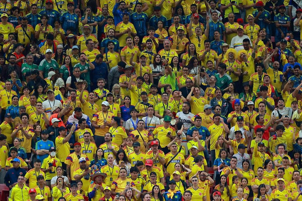 Crowd of sports fans in yellow jerseys cheering and celebrating in a stadium.