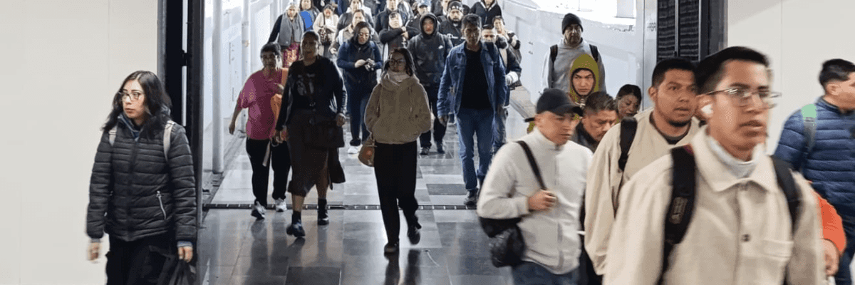 Crowd walking through a subway entrance, some wearing jackets and backpacks.