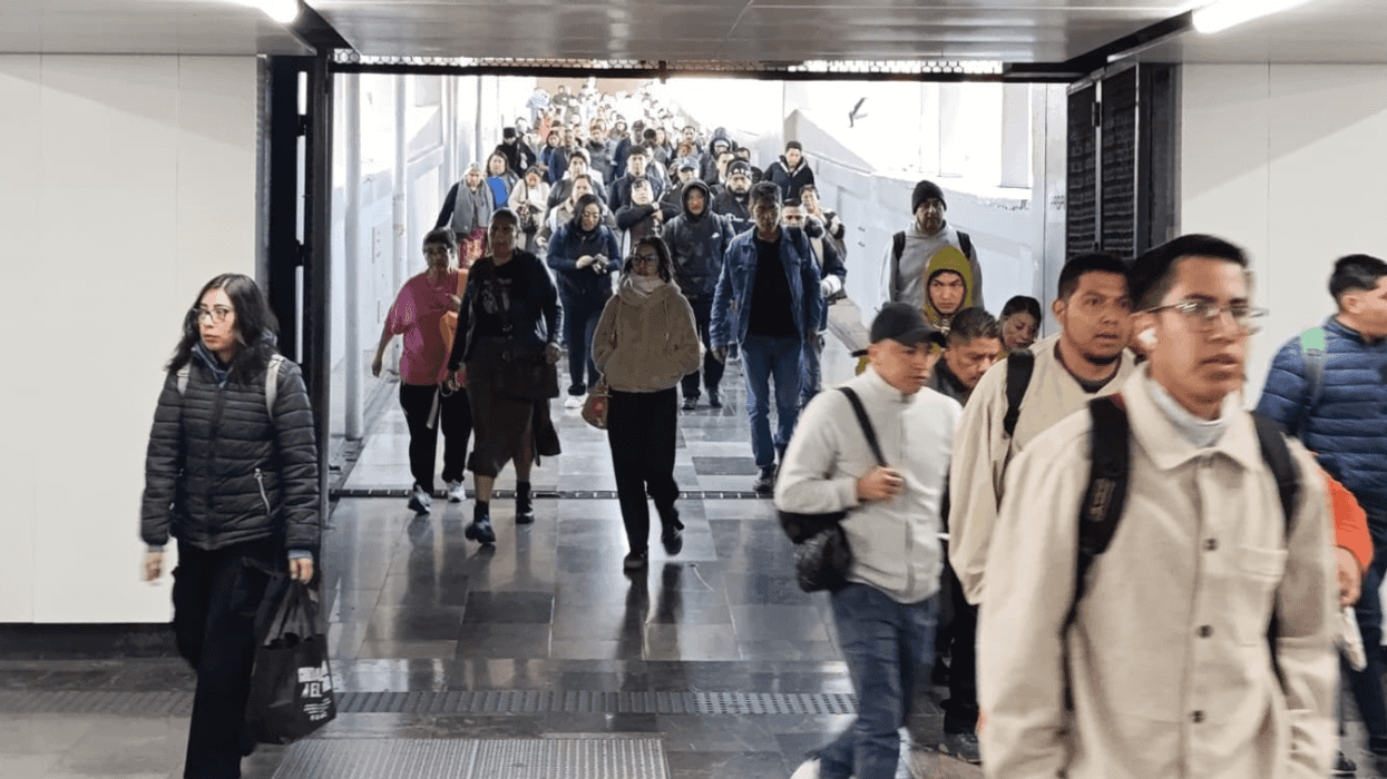Crowd walking through a subway entrance, some wearing jackets and backpacks.