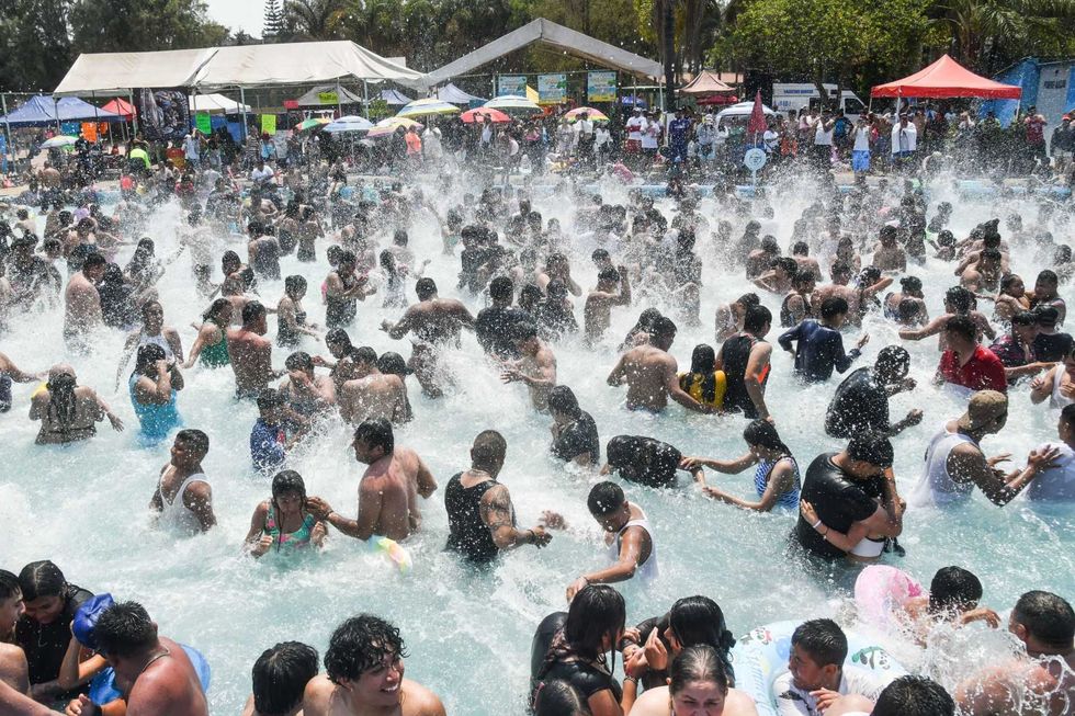 Crowded pool with people enjoying splashing water at a lively outdoor event.