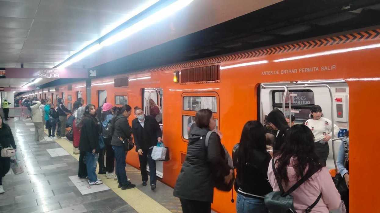 Crowded subway platform with people boarding an orange train.