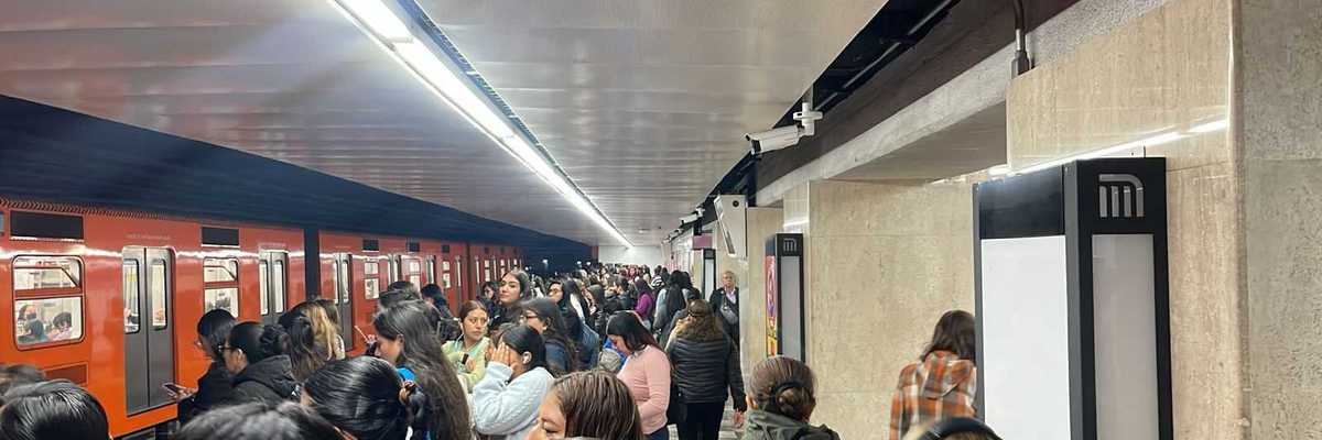 Crowded subway station platform with a train and many waiting passengers.