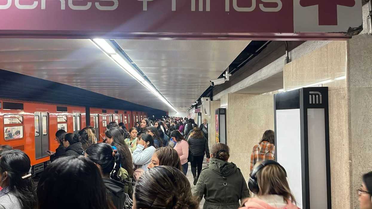 Crowded subway station platform with a train and many waiting passengers.