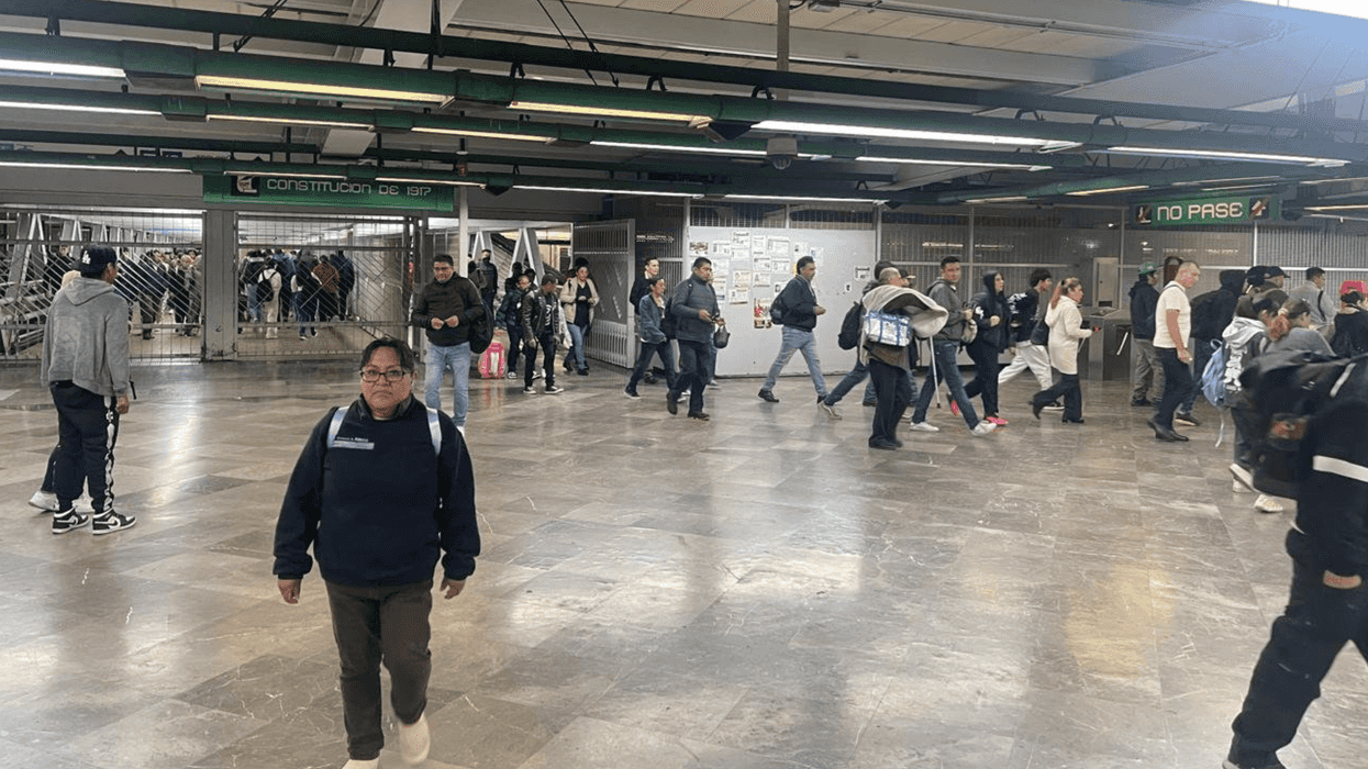 Crowded subway station platform with people walking in various directions.