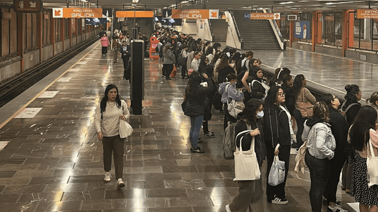 Crowded train platform with people waiting and one person walking away.