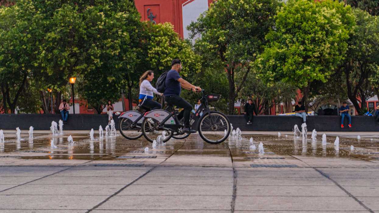 Dos jóvenes usuarios de Ecobici con bicicletas disponibles en Ciudad de México