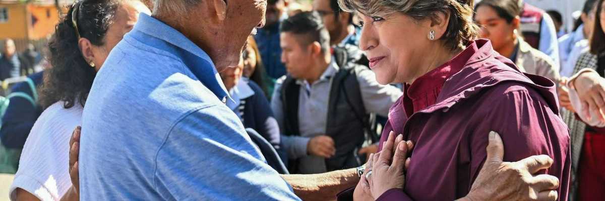 Elderly man and woman embracing, surrounded by a crowd outdoors.