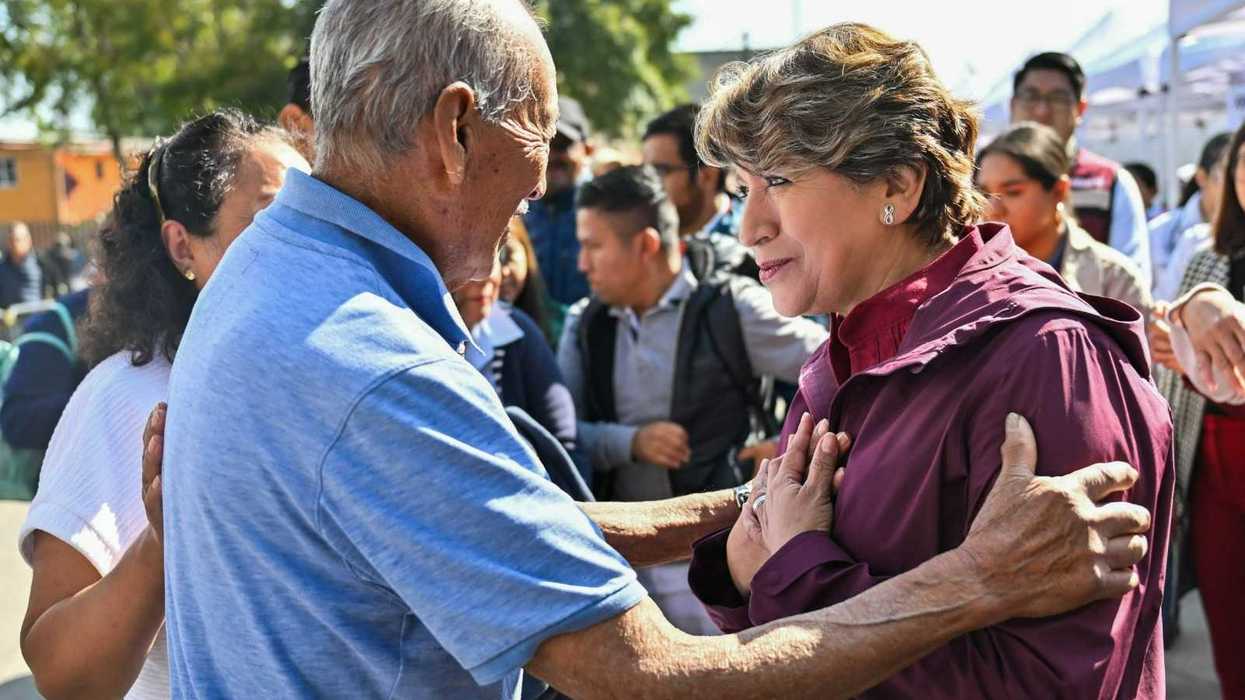 Elderly man and woman embracing, surrounded by a crowd outdoors.