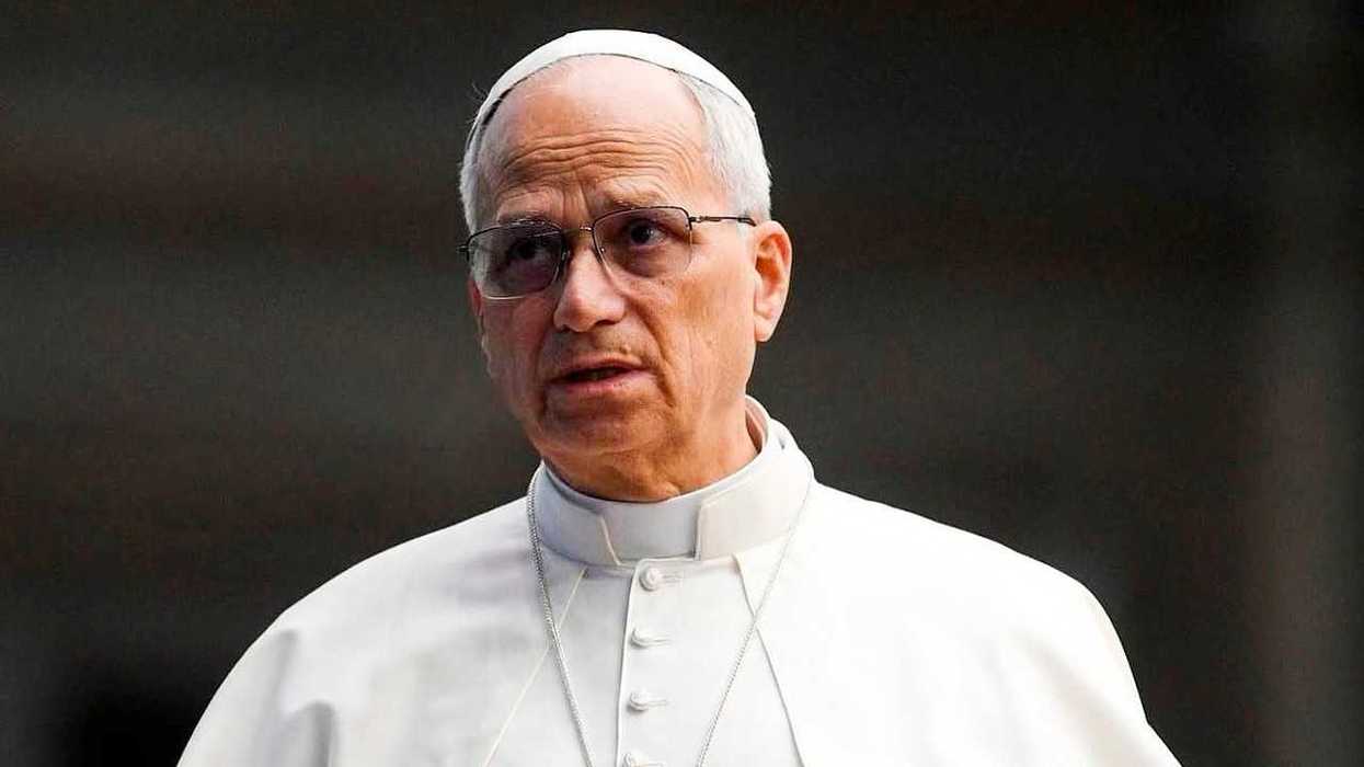 Elderly man in white religious attire and glasses, outdoors.