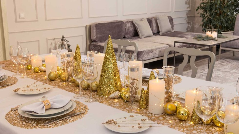 Elegant holiday table with gold decor, candles, and a cozy sofa in the background.