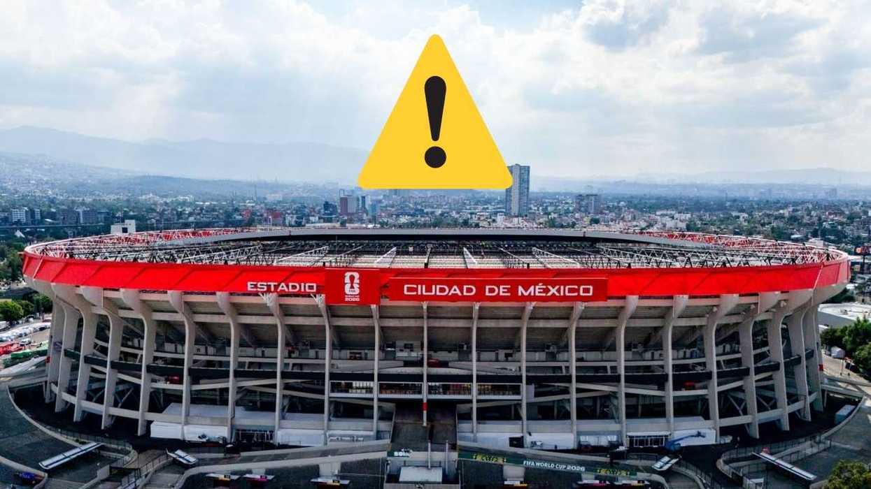 Estadio in Mexico City with warning sign above, cityscape in background.