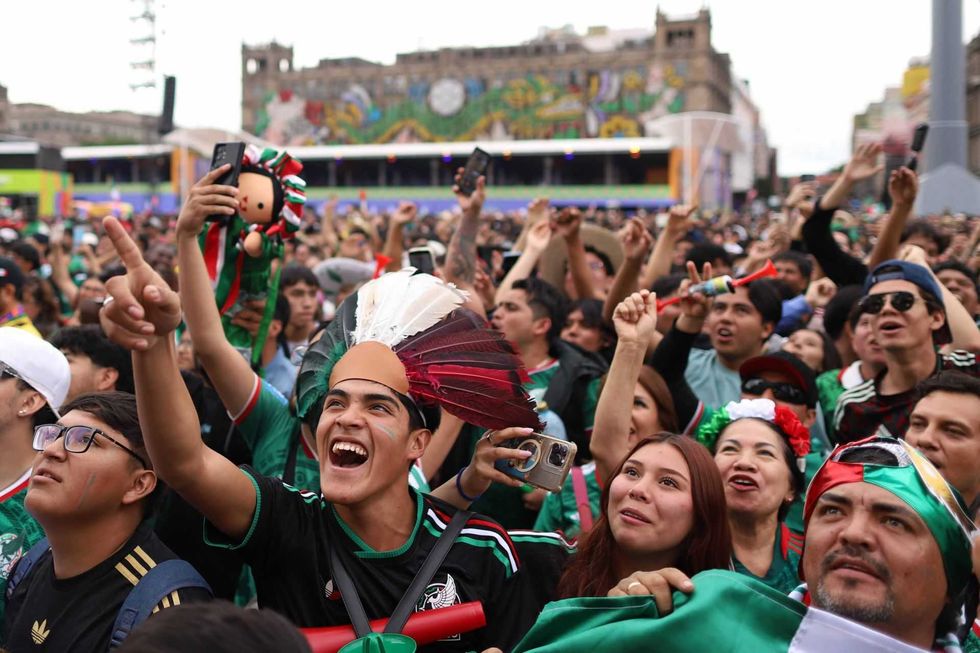 Excited crowd celebrates at an outdoor event, many wearing green and festive accessories.