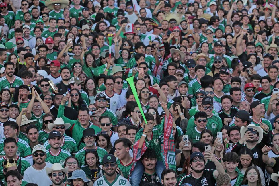 Excited crowd in green jerseys celebrating and taking photos at a sporting event.