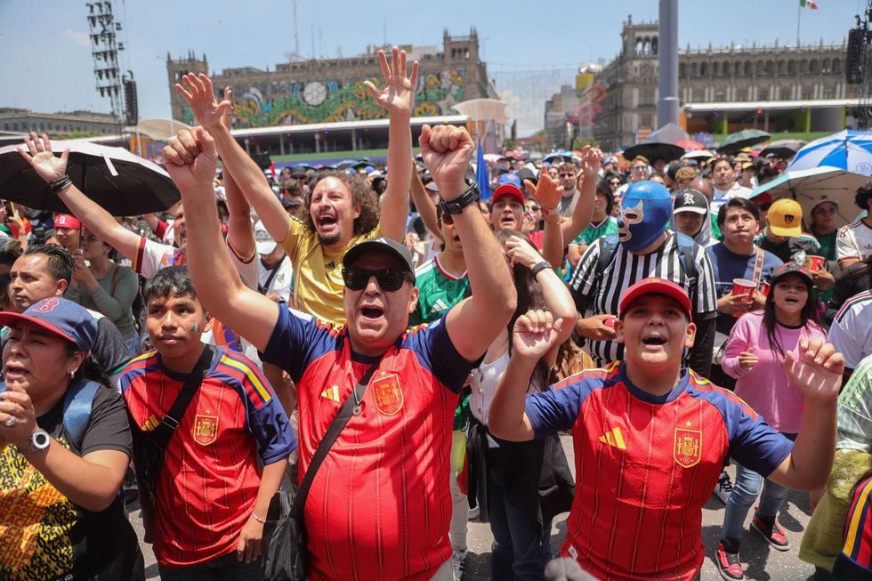 Excited crowd in sports jerseys cheering at an outdoor event.