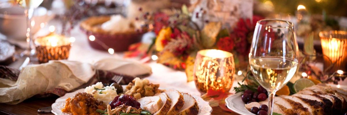 Festive dinner table with turkey, sides, wine, and glowing candles.