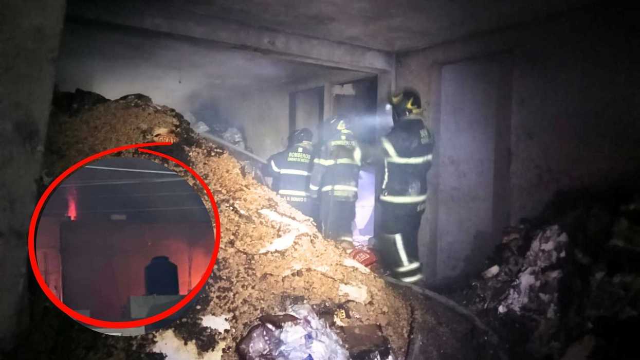 Firefighters extinguish flames in a debris-filled room, smoke and fire seen in the background.