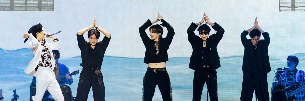 Five performers dancing energetically on stage with a vibrant background.