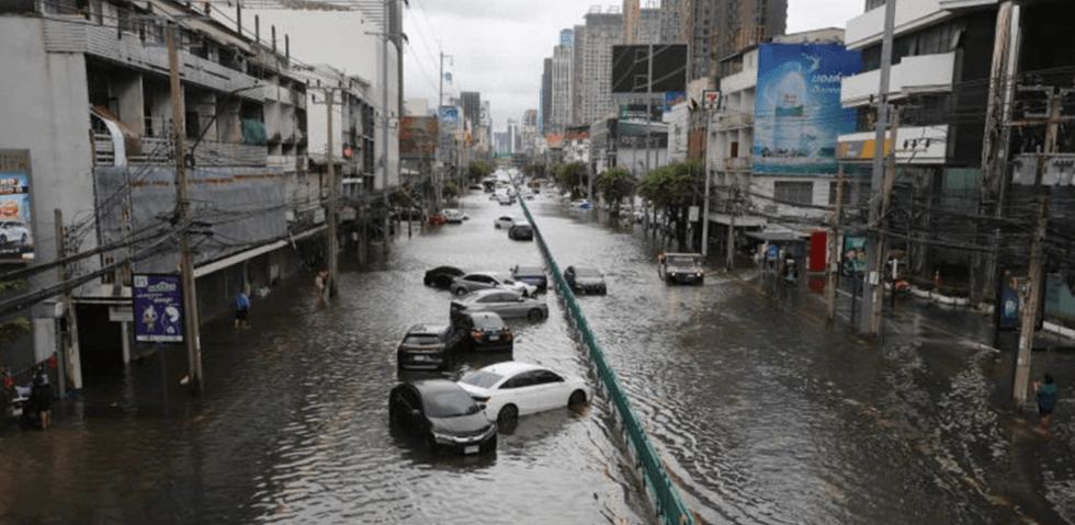 Flooded city street with submerged cars and buildings on both sides.