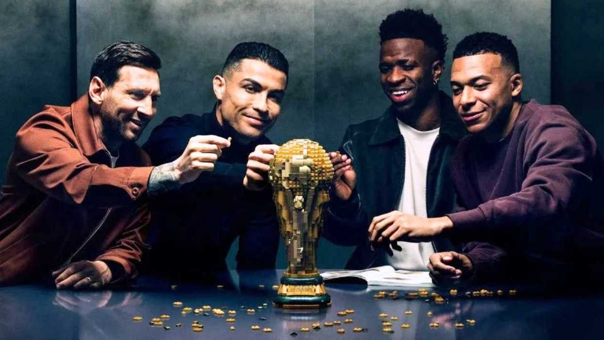 Four men assembling a golden trophy on a table, smiling and interacting.