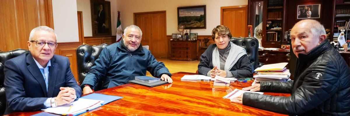 Four people in a conference room seated around a large wooden table.