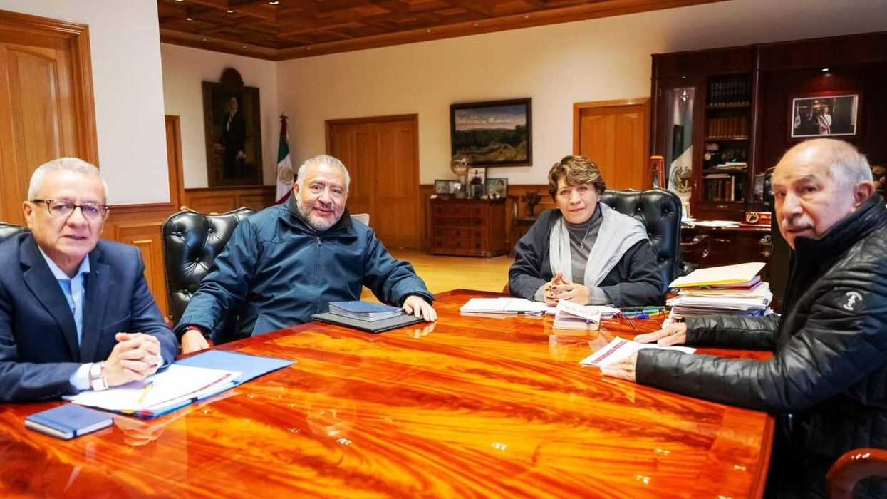 Four people in a conference room seated around a large wooden table.