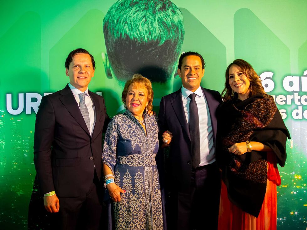 Four people posing before a green backdrop at an event.