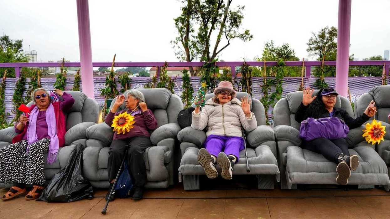 Four people relaxing on recliners, waving and holding flowers.
