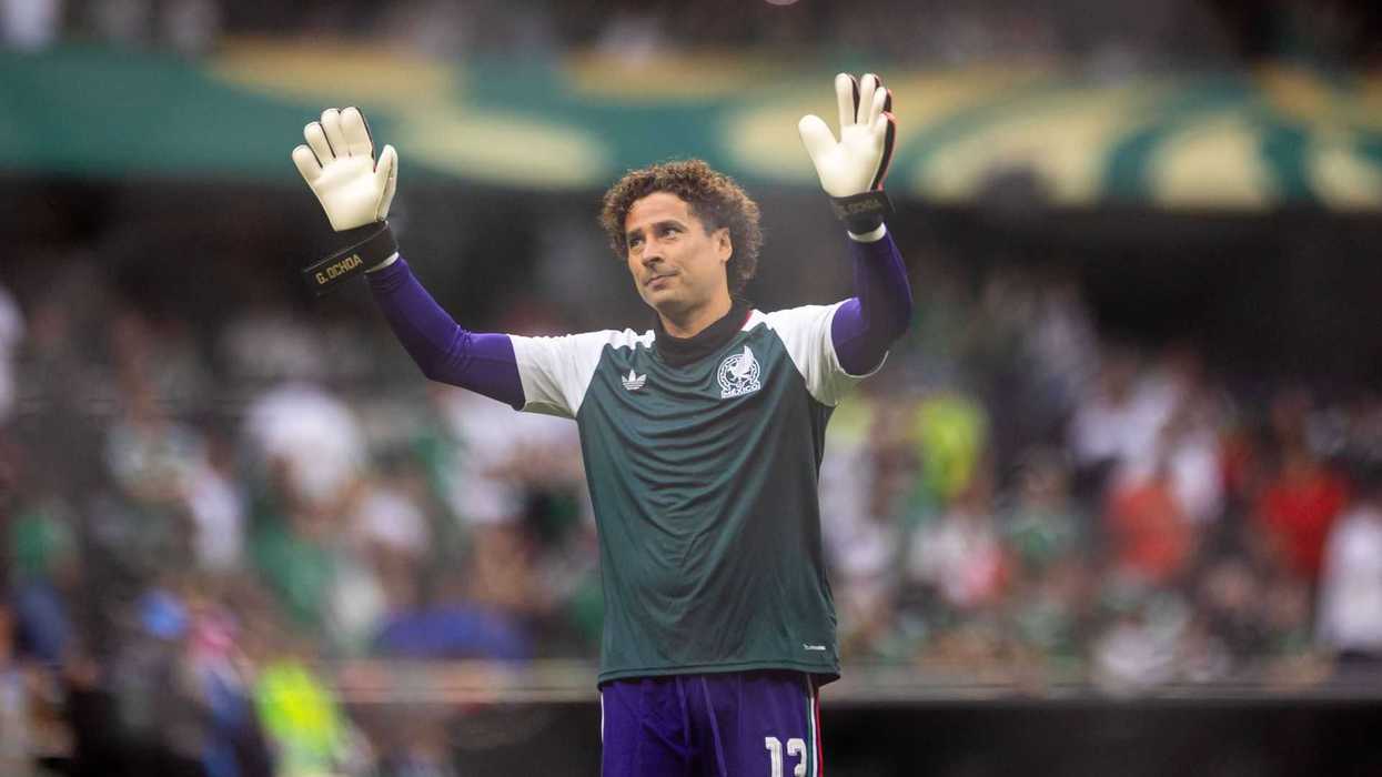 Goalkeeper waving to the crowd on a soccer field.
