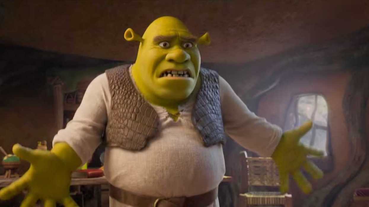 Green ogre with a concerned expression, wearing a vest, inside a cozy wooden dwelling.