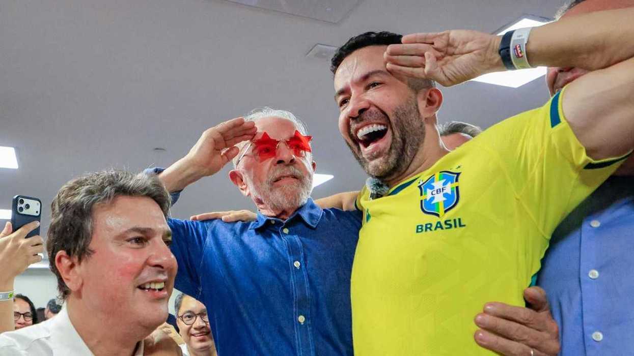 Group celebrates; man in red star glasses with arms around two others.