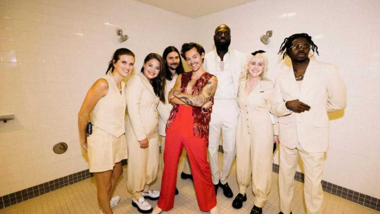Group in a tiled room, one person in a red outfit, others in white.