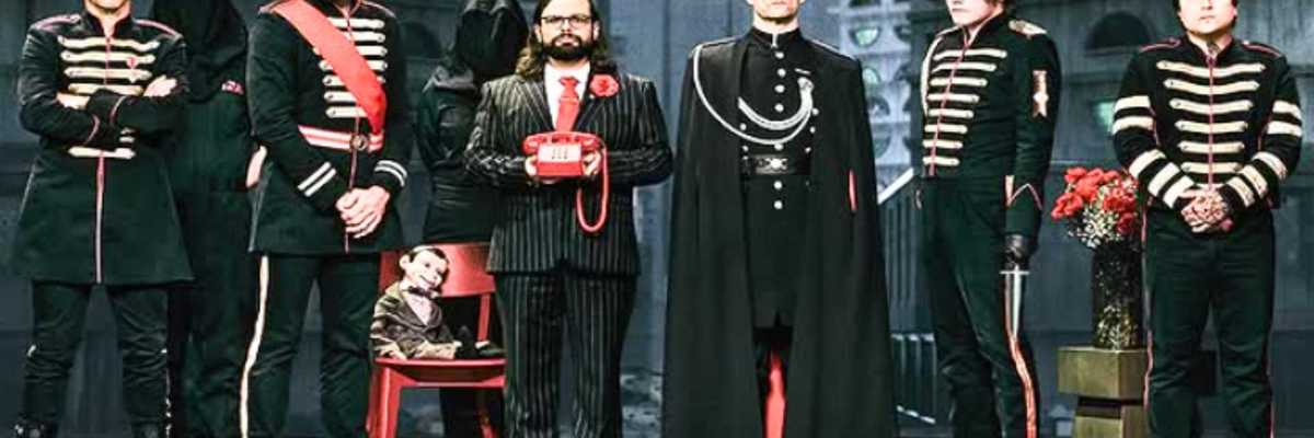 Group in military-style attire with a red phone, flowers, and a child-sized mannequin.