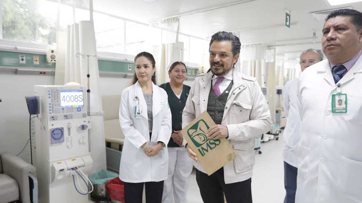 Group of healthcare professionals in a hospital ward, one holding a folder.