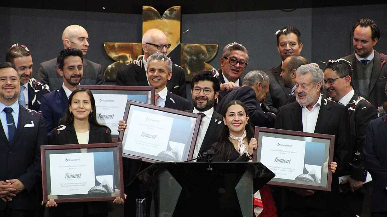 Group of people celebrating, holding framed awards, confetti falling around them.