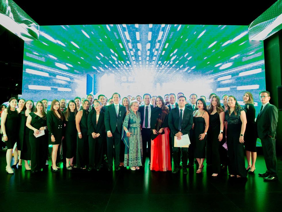 Group of people in formal attire posing in front of a vibrant, digital backdrop.