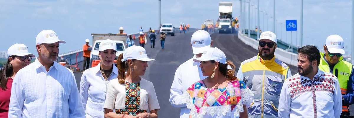 Group of people in hard hats walking on a newly constructed bridge.