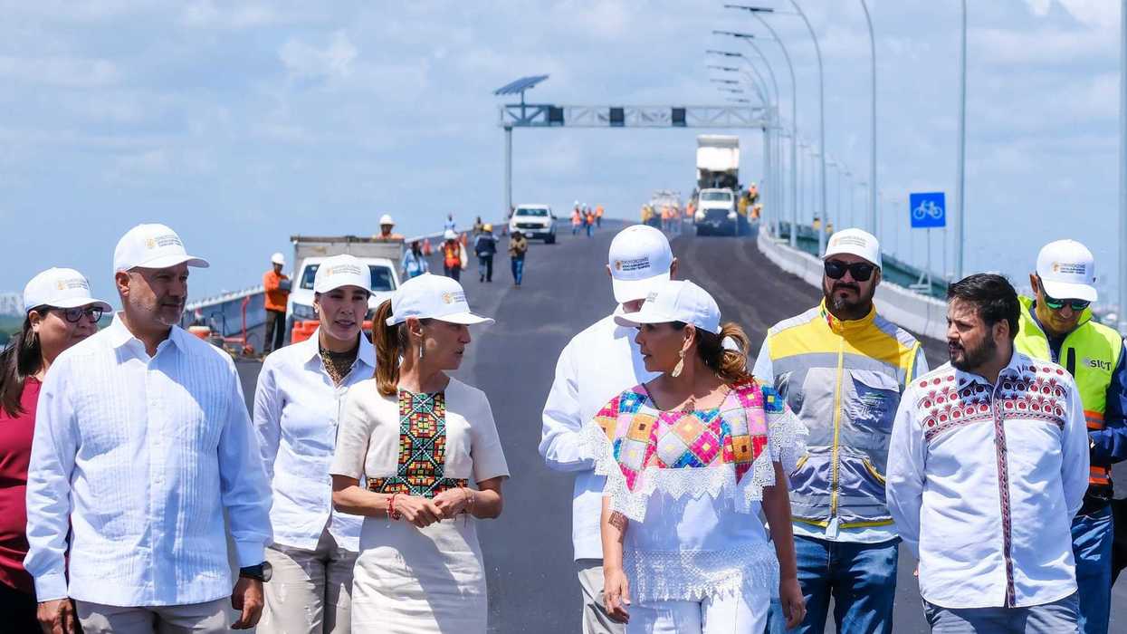 Group of people in hard hats walking on a newly constructed bridge.