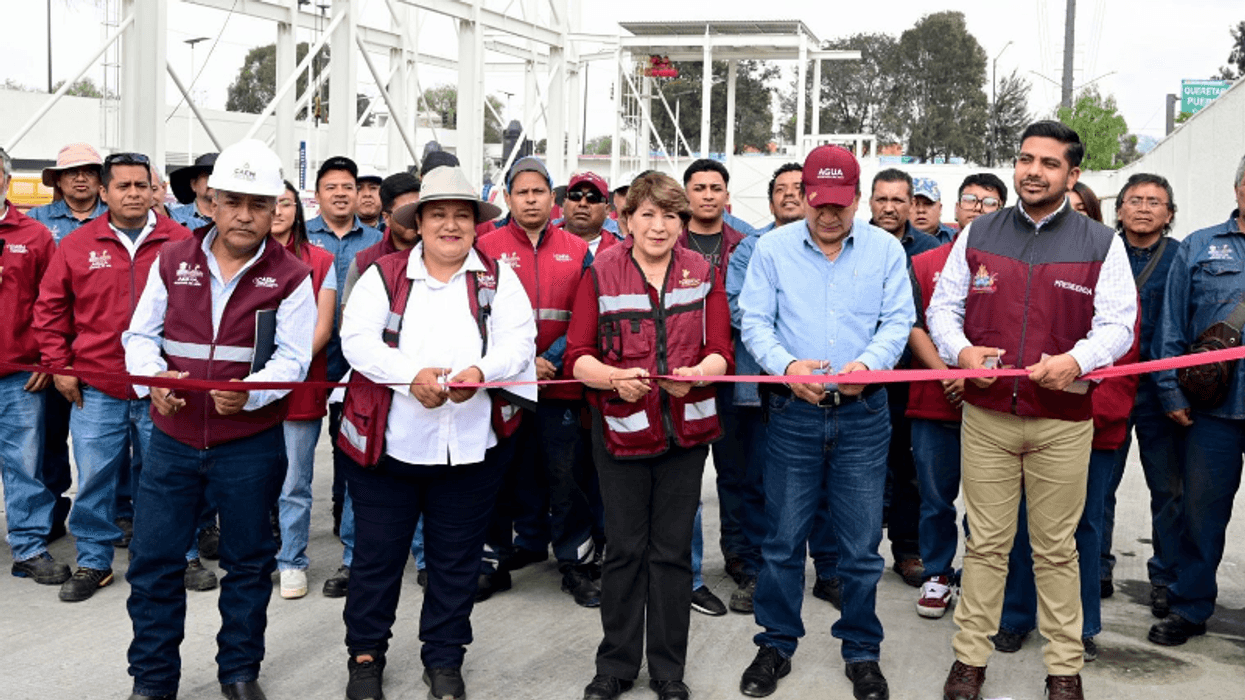 Group of people in vests cutting a ribbon at an outdoor event.
