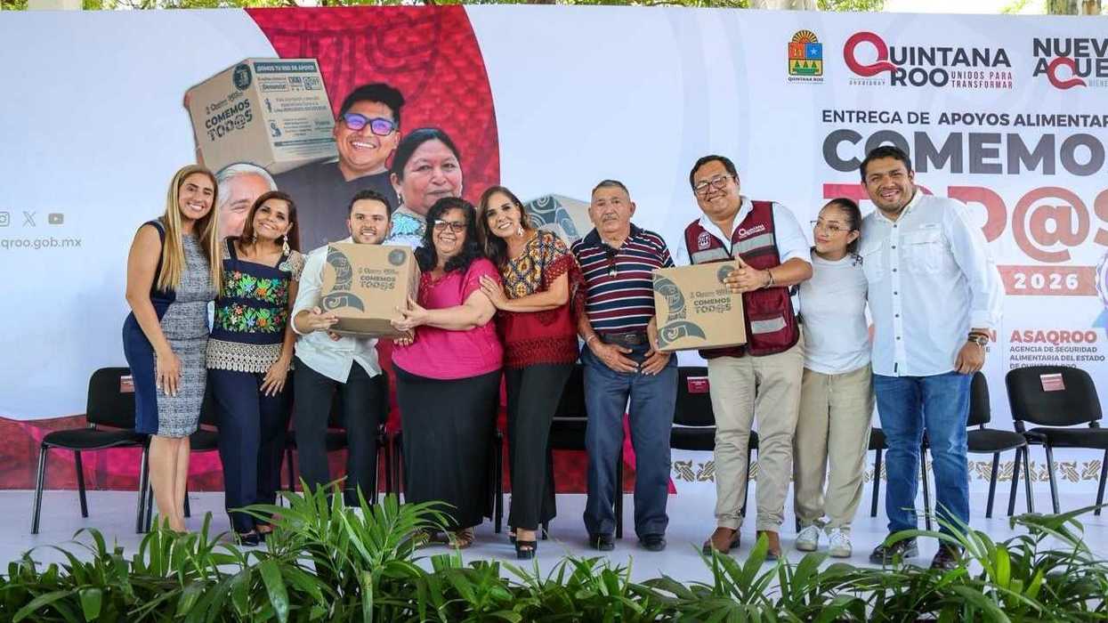 Group of people smiling with food aid boxes at a Quintana Roo event.