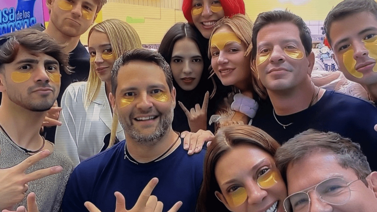 Group of smiling people wearing yellow under-eye patches indoors.