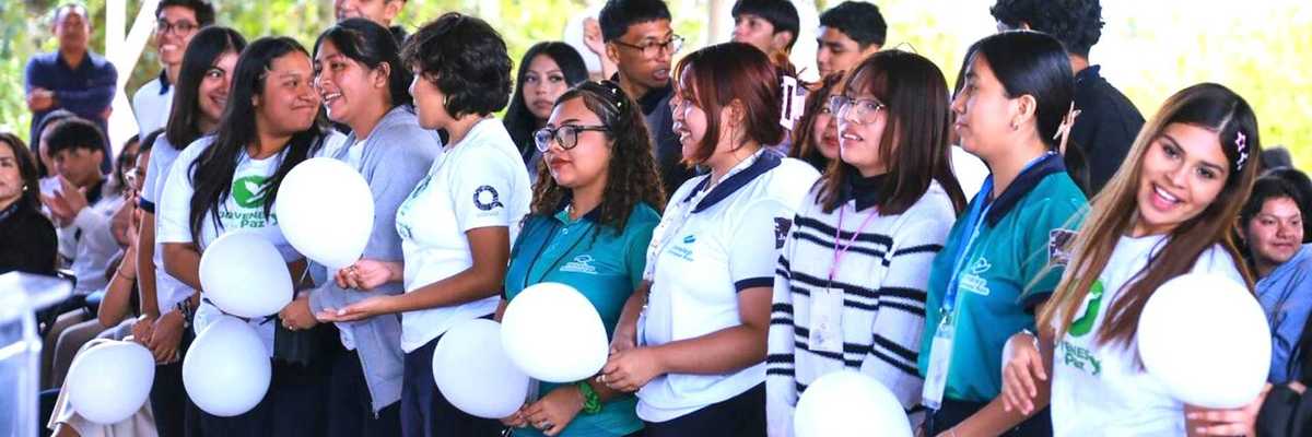 Group of students holding white balloons at an outdoor event.