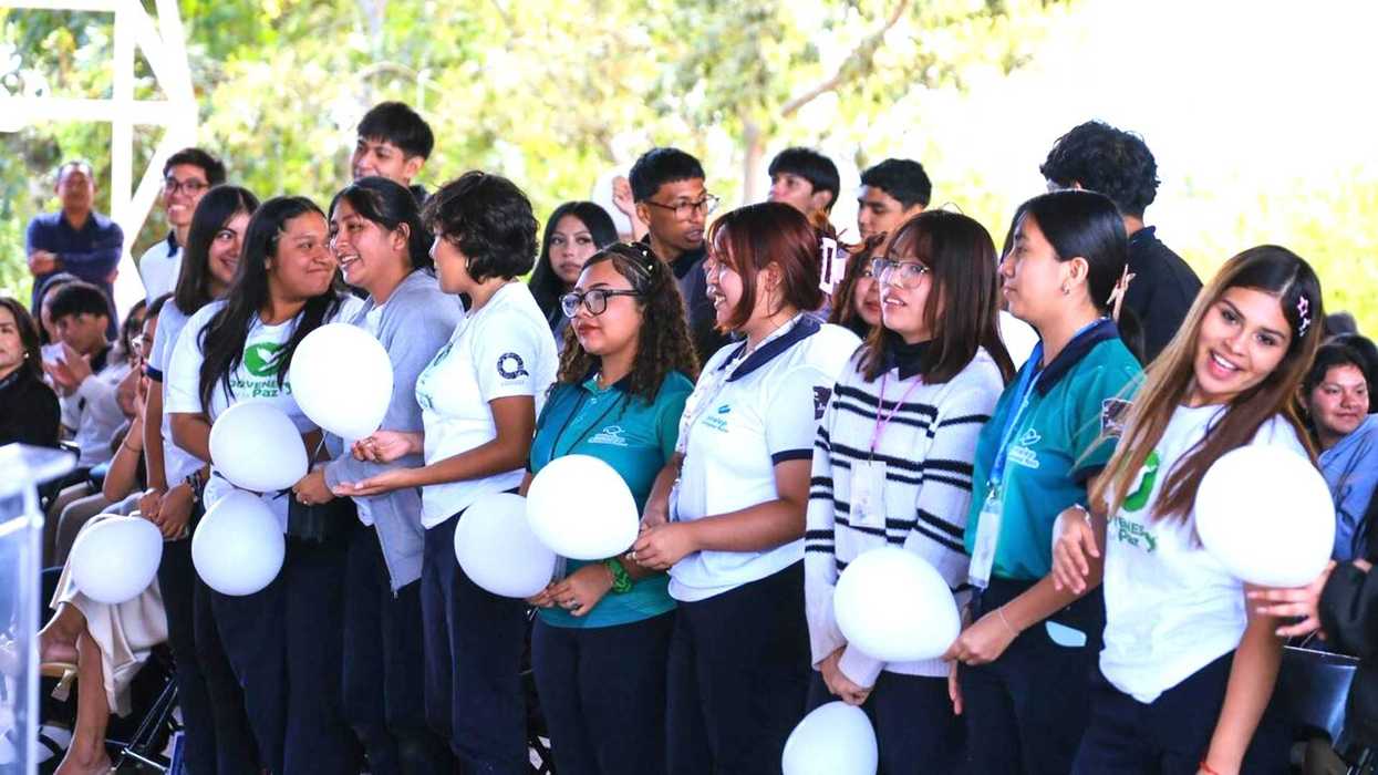 Group of students holding white balloons at an outdoor event.