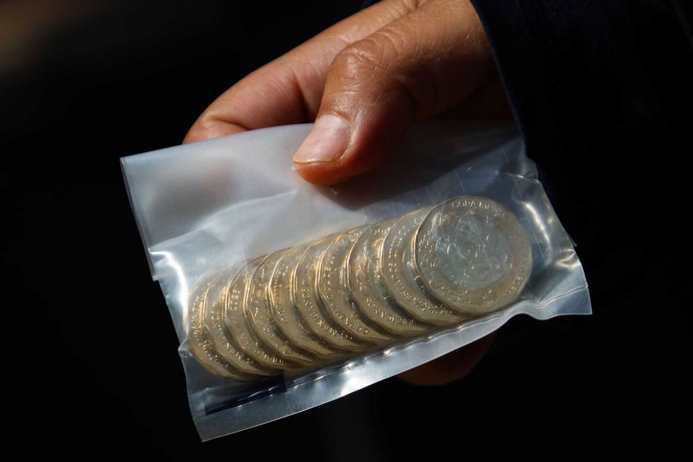 Hand holding a clear bag with stacked coins.