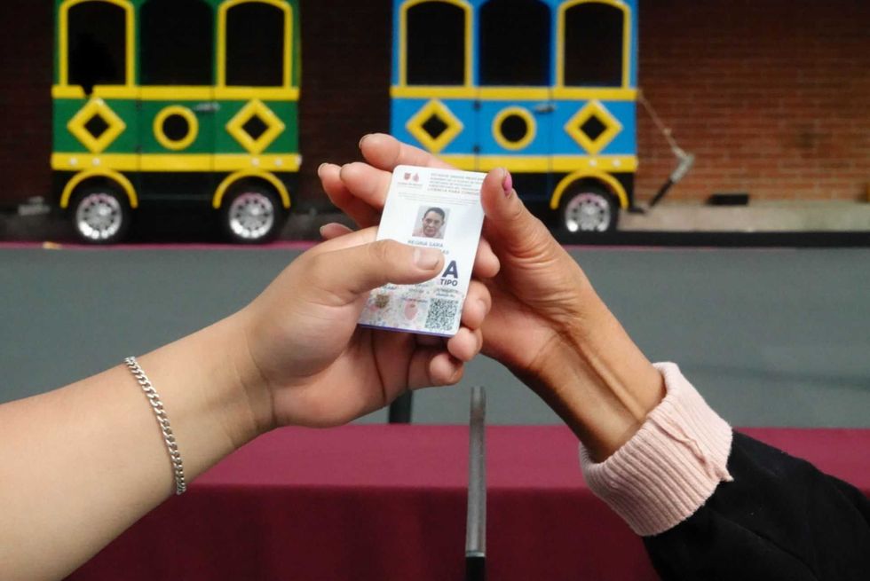 Hands exchanging an ID card, colorful background with toy train.