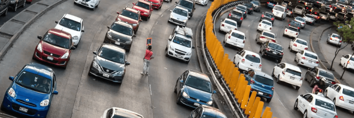 Heavy traffic fills a multi-lane highway, divided by bright orange barriers.