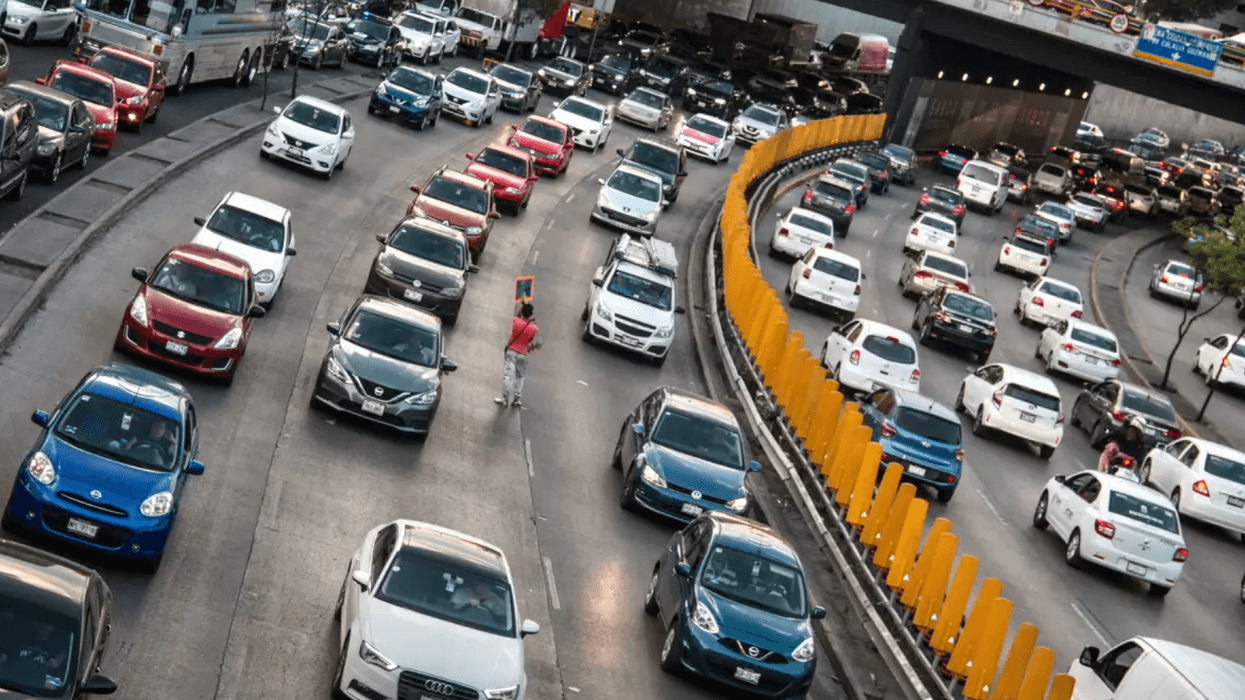 Heavy traffic fills a multi-lane highway, divided by bright orange barriers.