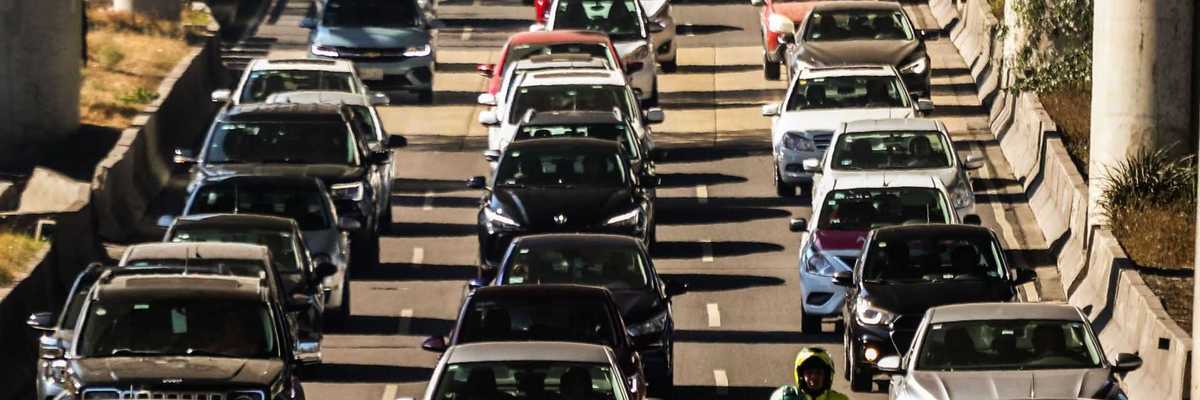 Heavy traffic with cars and a motorcycle on a multi-lane highway.