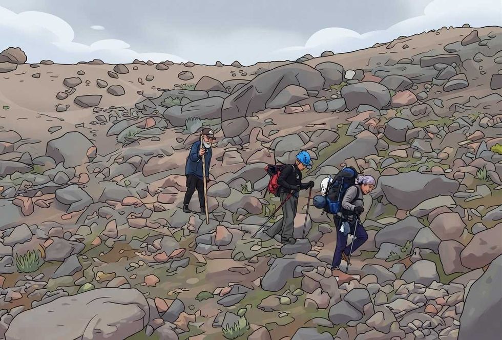 Hikers traverse rocky, barren landscape under cloudy skies, using poles for support.