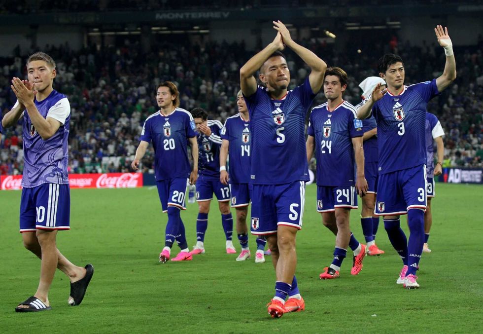 Japanese soccer team clapping to fans in a stadium after a match.